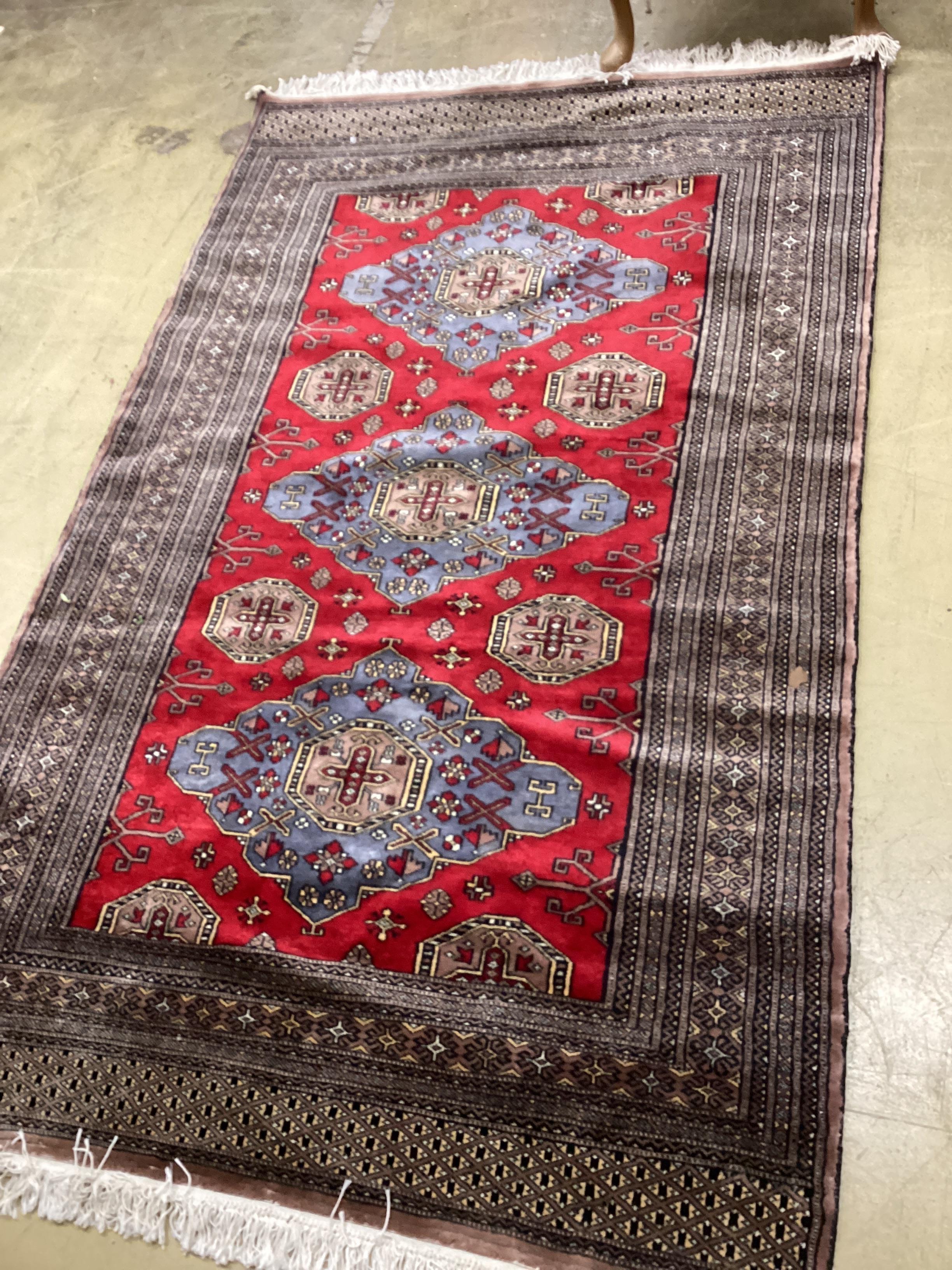 A Pakistan red ground triple medallion rug, 200cm x 126cm.